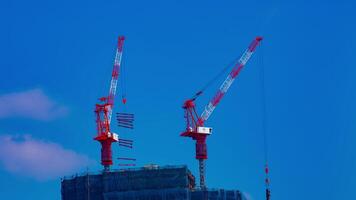 A timelapse of cranes at the under construction behind the blue sky in Tokyo video