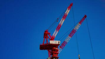 un' lasso di tempo di gru a il sotto costruzione dietro a il blu cielo nel tokyo video