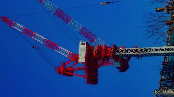 A timelapse of cranes at the under construction behind the blue sky in Tokyo vertical video