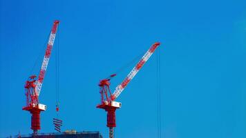 A timelapse of cranes at the under construction behind the blue sky in Tokyo video