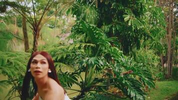 sorprendido mujer en un tropical jardín mirando terminado su hombro. video