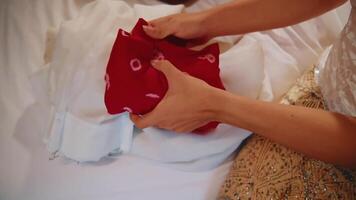 detailopname van handen regelen van traditioneel bruiloft kleding met ingewikkeld details en levendig kleuren. video