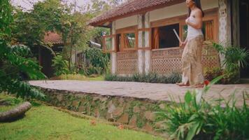 tradicional balinés bailarín ejecutando en un tropical jardín ajuste con un pintoresco villa fondo. video