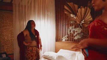 Two women in traditional attire talking in a room with elegant decor. video