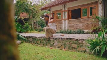 kvinna praktiserande yoga i en fredlig trädgård miljö. video