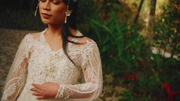 Elegant woman in a white lace dress standing in a lush garden video