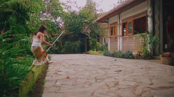 criança jogando com bastão dentro frente do uma rústico casa, cercado de exuberante vegetação. video
