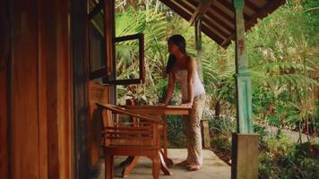 kvinna avkopplande på en veranda i en tropisk miljö. video