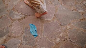 Child stepping out of a small shoe on a textured stone pavement video