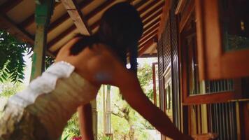 Serene tropical setting with a woman cleaning the wooden desk, surrounded by lush greenery. video