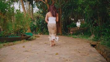 Woman running on a rustic path by the river, surrounded by lush greenery video