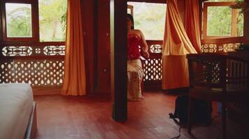 Woman standing in a rustic room with wooden decor and warm lighting. video