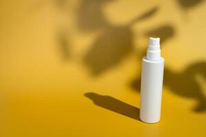 Blank white spray bottle with plant leaf shadow photo