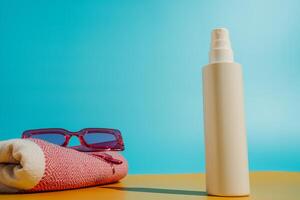 blanco protector solar botella playa toalla y Gafas de sol en playa foto