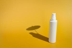Blank white spray bottle with umbrella shadow in direct sunlight photo