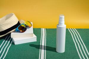 blanco protector solar botella Dom sombrero y Gafas de sol libros en playa toalla foto