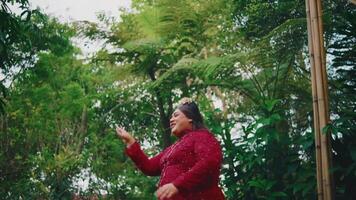 Woman in red dress dancing in tropical garden setting. video