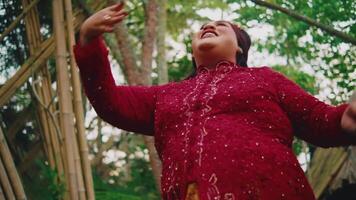vrouw in rood jurk dansen in tropisch tuin instelling. video