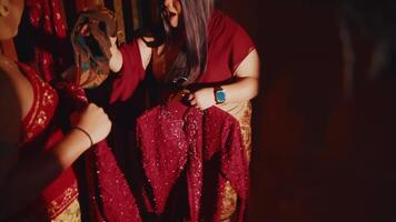 deux femmes sélection une traditionnel rouge robe, peut-être pour une culturel un événement ou la cérémonie video