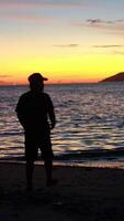 silhouette de une homme permanent sur le plage à lever du soleil video