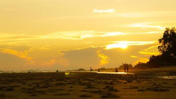 Silhouette of a group of friends enjoying the sunset on the beach at golden sunset time, relaxing on a relaxing vacation, sea in the evening. photo