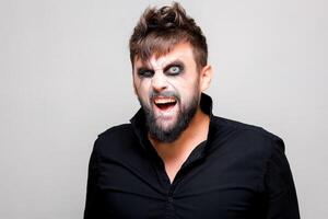 undead-style makeup on a bearded man who looks from under his brows and grimaces photo