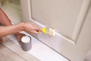 The process of painting doors white with a brush. Repair staining the doors with paint. photo
