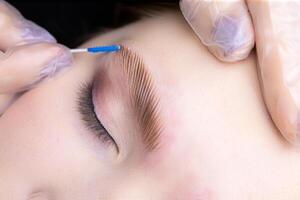 shaping and directing the growth of eyebrows with a brush after the eyebrow lamination procedure photo