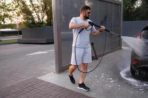 A man washes a car with a water cannon running around it. A car at a self service car wash. photo