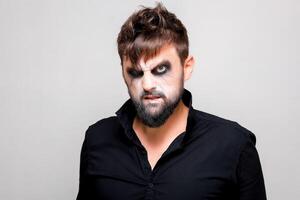 undead-style makeup on a bearded man who looks from under his brows and grimaces photo