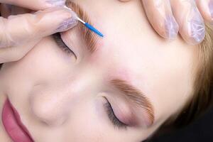 shaping and directing the growth of eyebrows with a brush after the eyebrow lamination procedure photo