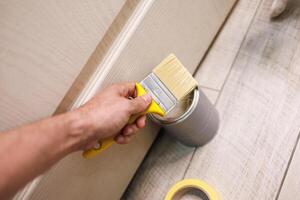 In hand is a paint brush for painting doors and repairs. Repair staining the doors with paint. photo