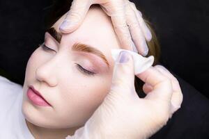 in the hands of the master is a cotton sponge with which he removes the remnants of paint from painted eyebrows photo