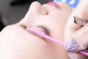 combing laminated eyebrows with a brush photo