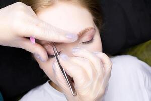 correction and plucking of excess hairs after the eyebrow lamination procedure photo
