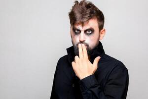 a man with a beard and undead makeup on Halloween holds his hands in front of him photo