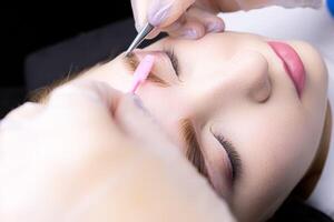 macro photography thinning of eyebrow hairs in the hands of the master there are tweezers and a brush photo