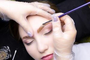 applying paint to the model's eyebrows with a brush after lamination photo