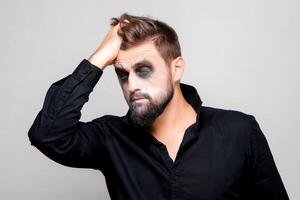 Víspera de Todos los Santos y maquillaje para un barbado hombre quien lágrimas el pelo en su cabeza foto