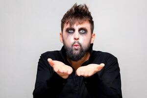 a man with a beard and undead makeup on Halloween holds his hands in front of him photo