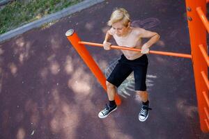 Athletic teens on a horizontal bar perform acrobatic exercises. Street workout on a horizontal bar in the school park. photo