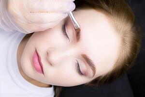 applying hair dye to the eyebrows of the model photo