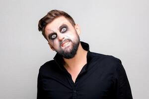 undead makeup for October 31 on a bearded man who shows teeth photo