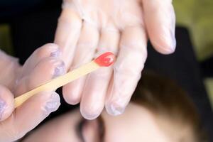 there is wax on a wooden stick to remove excess hairs from the eyebrows photo