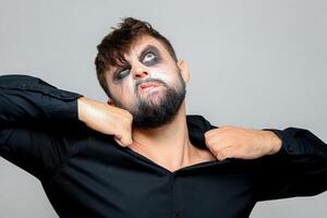 undead-style makeup on a rich man who holds on to the collar of his shirt with his hands photo