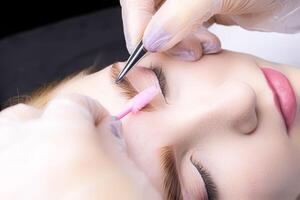 macro photography thinning of eyebrow hairs in the hands of the master there are tweezers and a brush photo