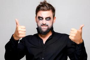 Bearded man with undead makeup gives a thumbs up photo