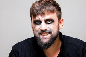 a man with undead-style makeup laughs and shows his teeth photo