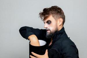 A bearded man with undead-style makeup opens a black box for Halloween photo