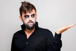 a man with a beard and undead makeup on Halloween holds his hands in front of him photo